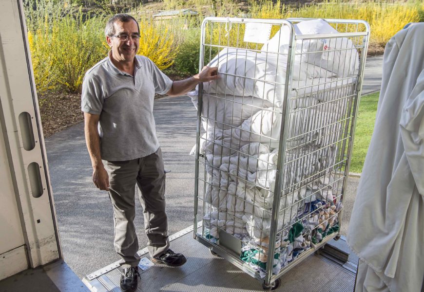Ali Cütcü schiebt einen große Gitterwagen voller Wäsche auf die Laderampe eines LKW