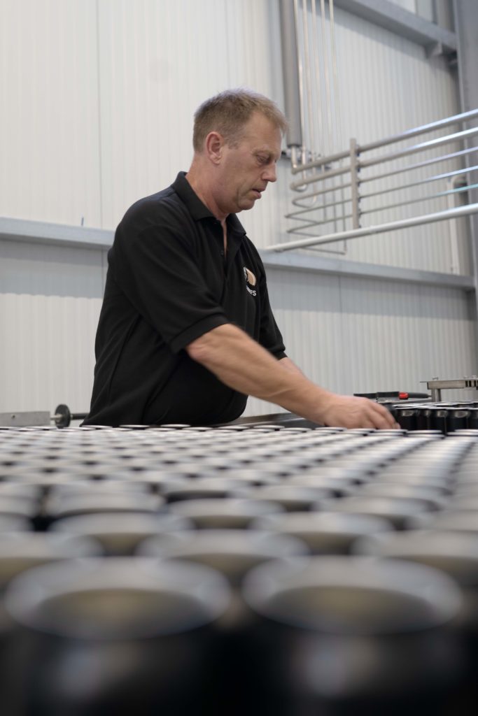 Ein Mitarbeiter sortiert Bierdosen an einer Endstation der Produktion in der Josefsbrauerei.